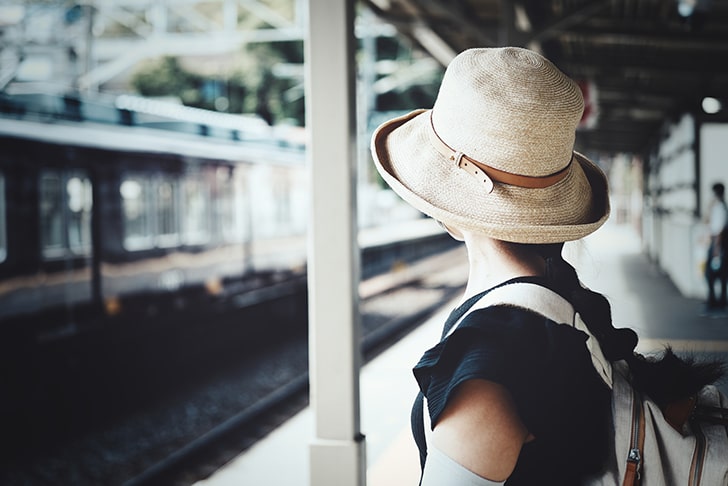 電車を待つ帽子をかぶった女性