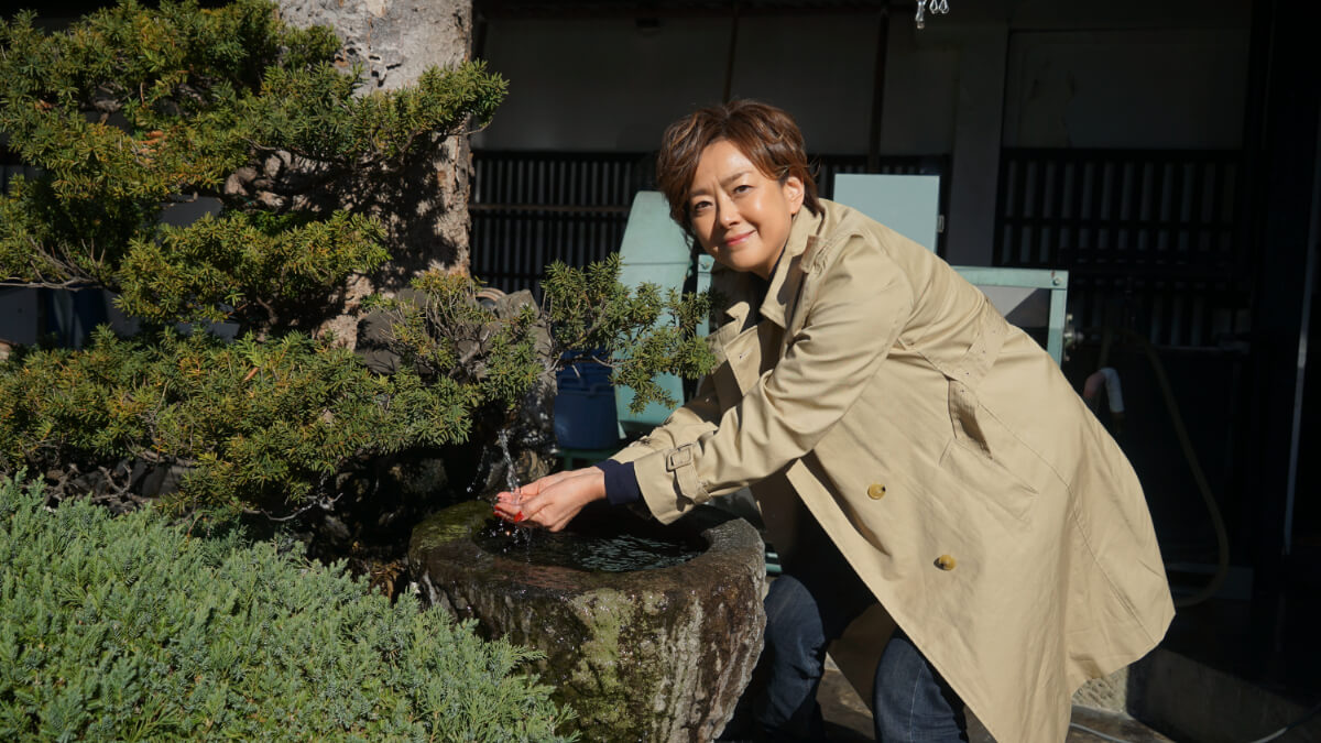 武甲山の伏流水に触れる歌手の秋本奈緒美さん