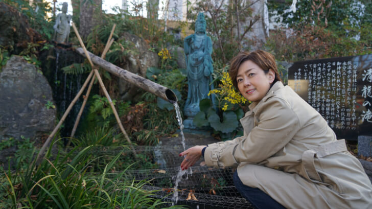 武甲山の伏流水に触れる歌手の秋本奈緒美さん