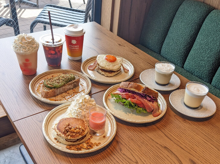 テーブルに並べられたサンドイッチ、パンケーキ、コーヒー、プリン